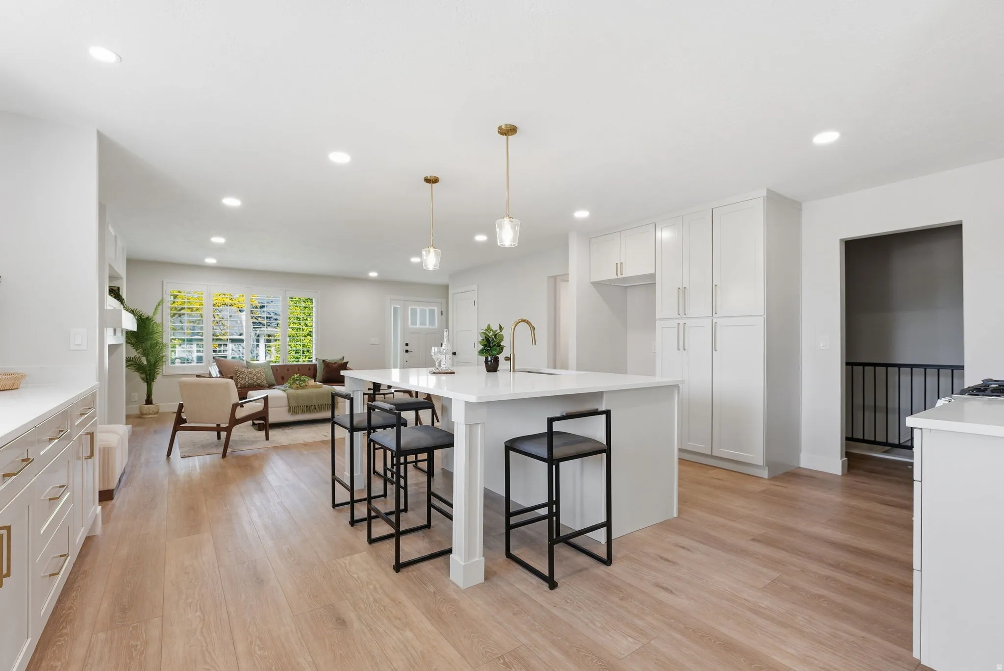 Open-concept living area featuring wood-finish flooring, recessed lighting, and a kitchen island with seating