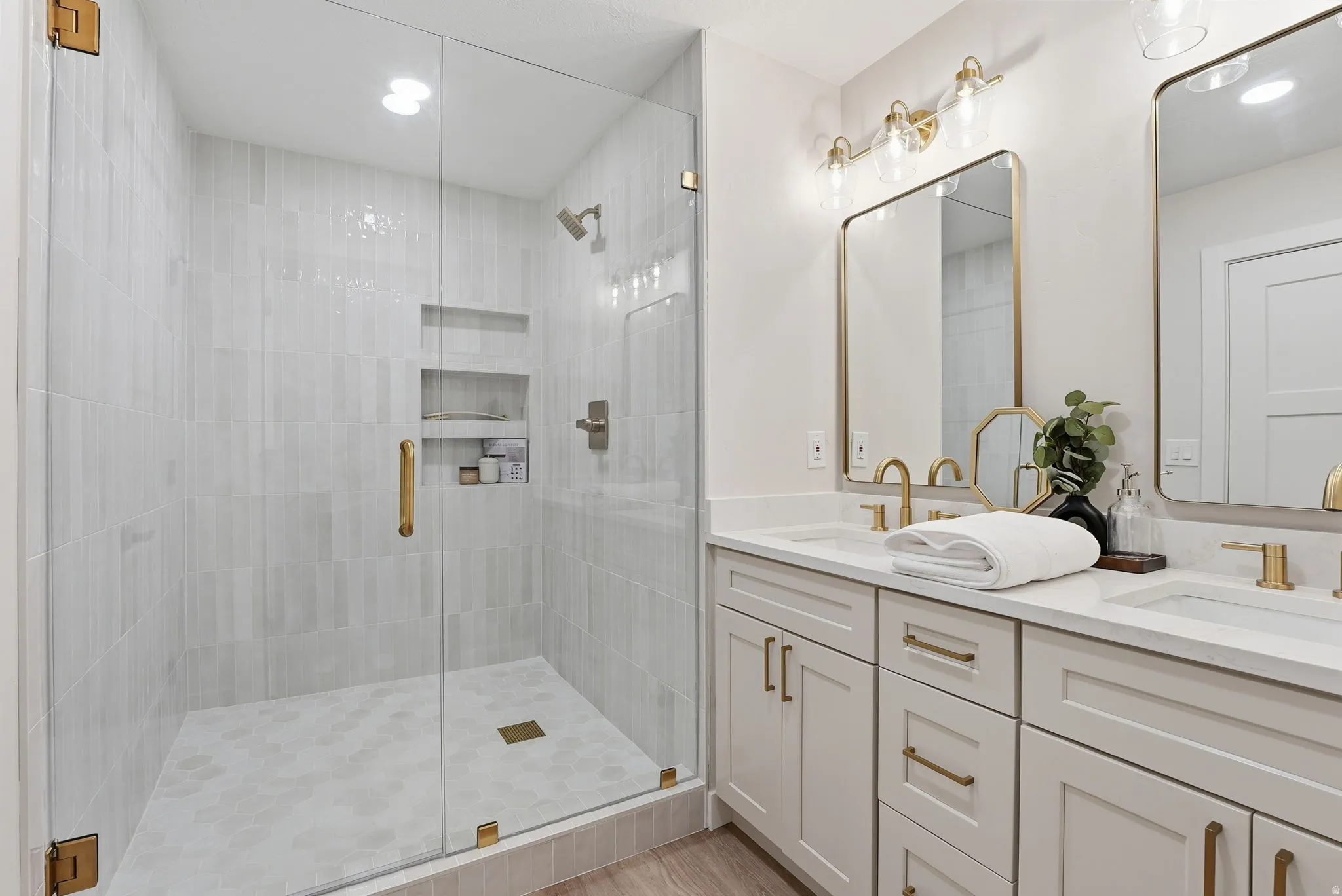 Glass-enclosed shower with wall-mounted fixtures and recessed shelving
