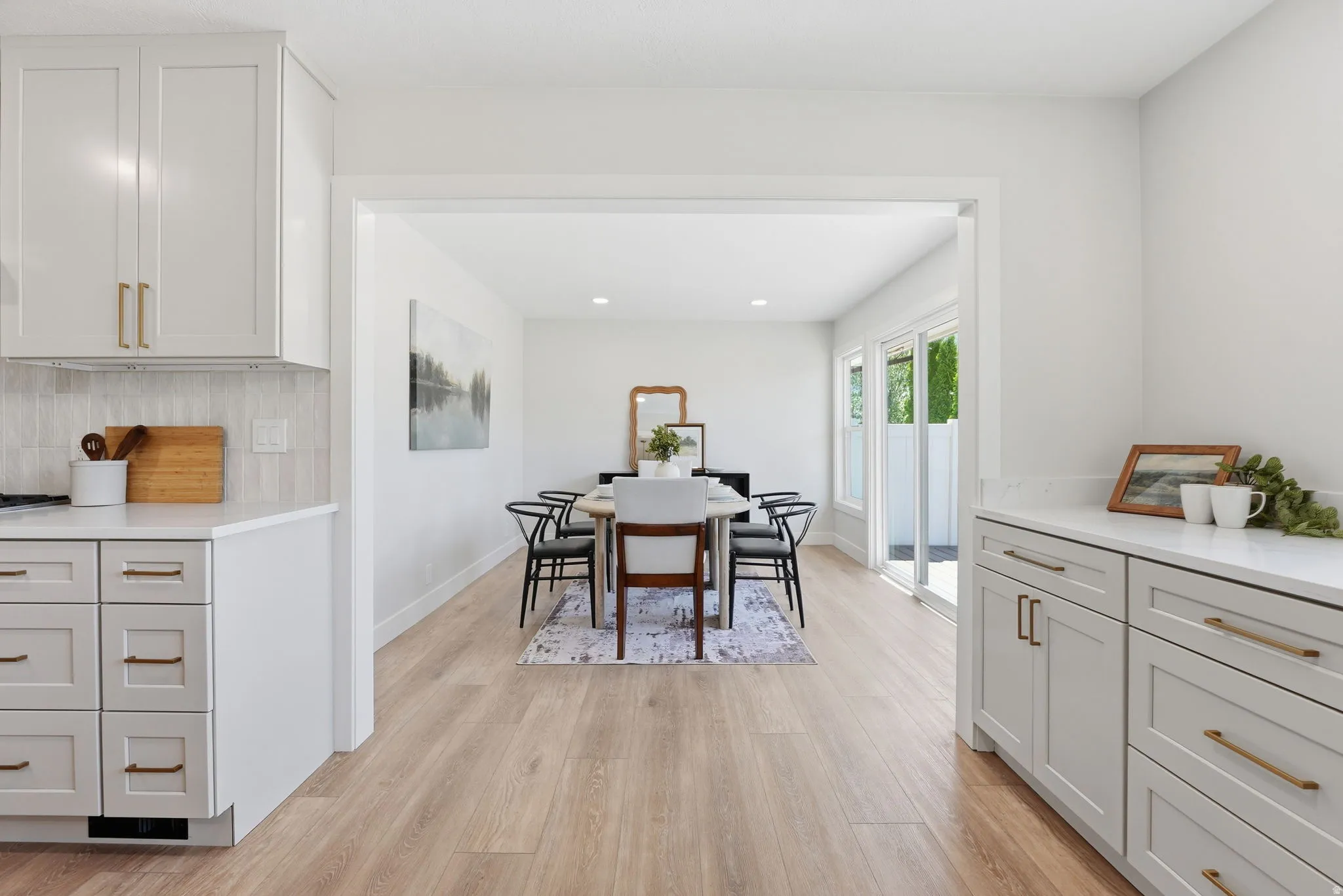 Open concept dining area with light wood-finish flooring, white walls, and a recessed lighting fixture