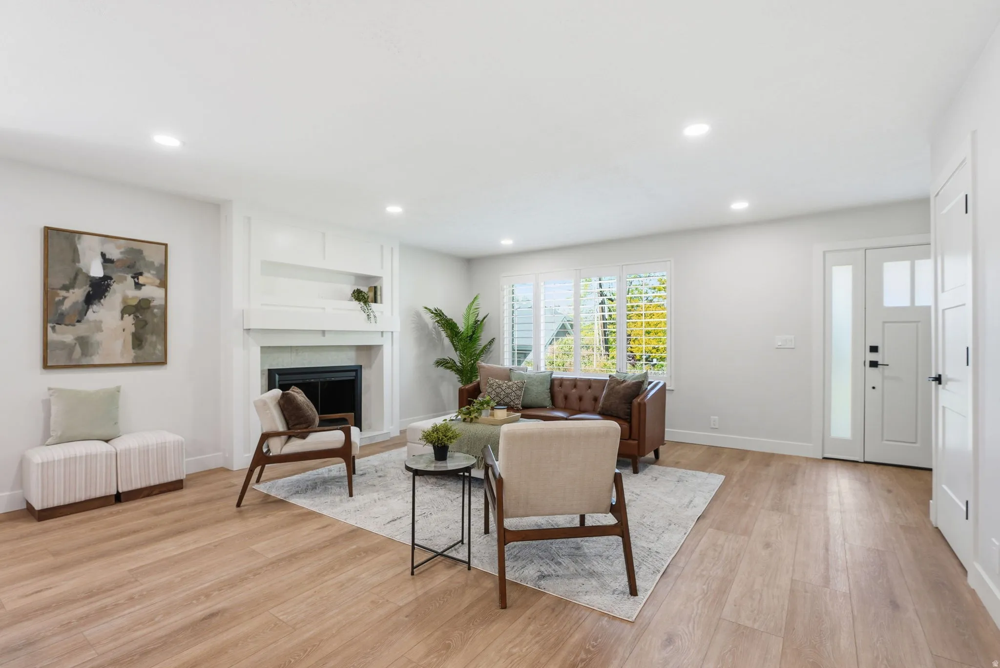 Spacious living area featuring wood-finish flooring, recessed lighting, and a white fireplace with built-in shelving