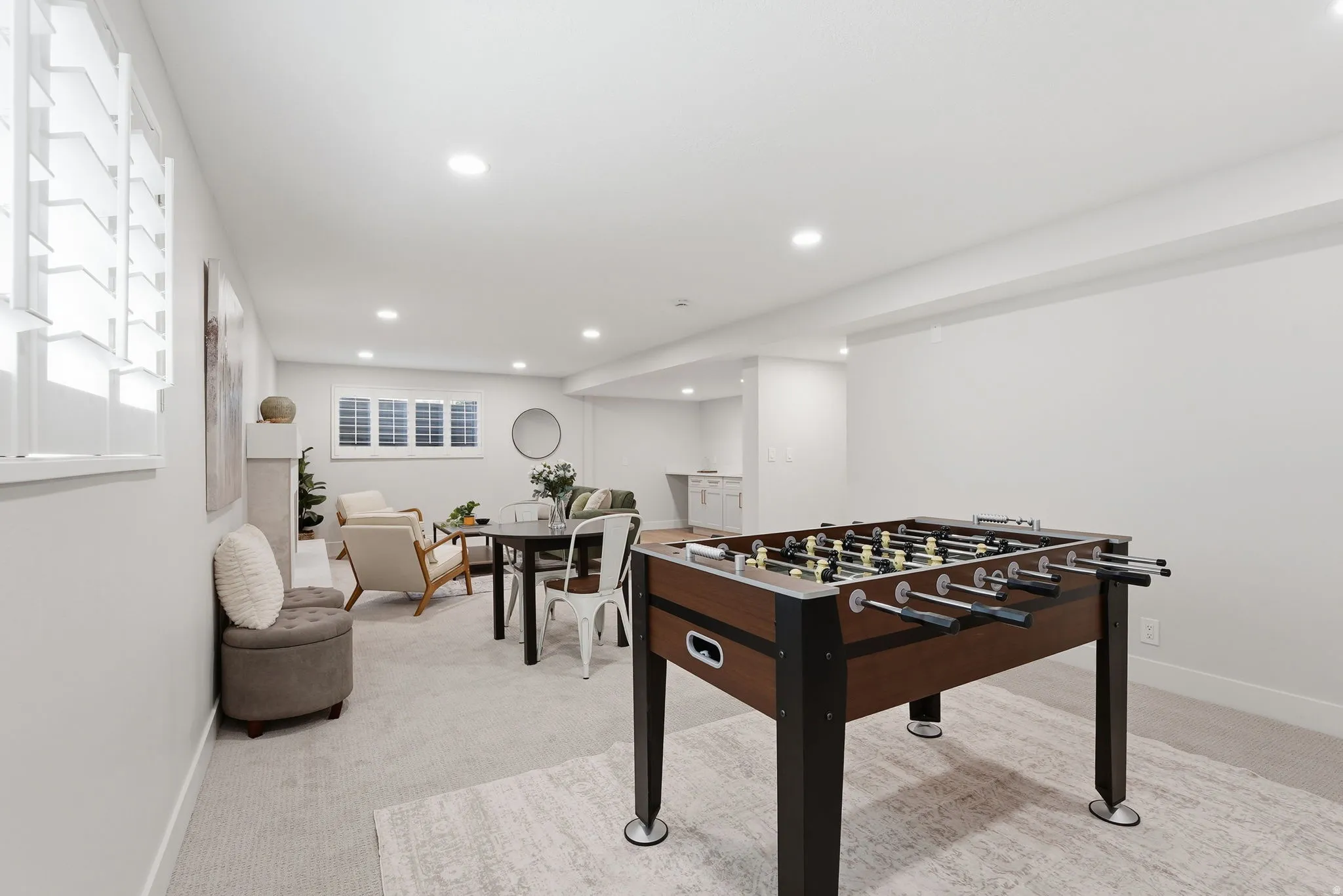 Spacious open-concept room featuring recessed lighting, light-toned carpeting, and multiple windows with plantation shutters