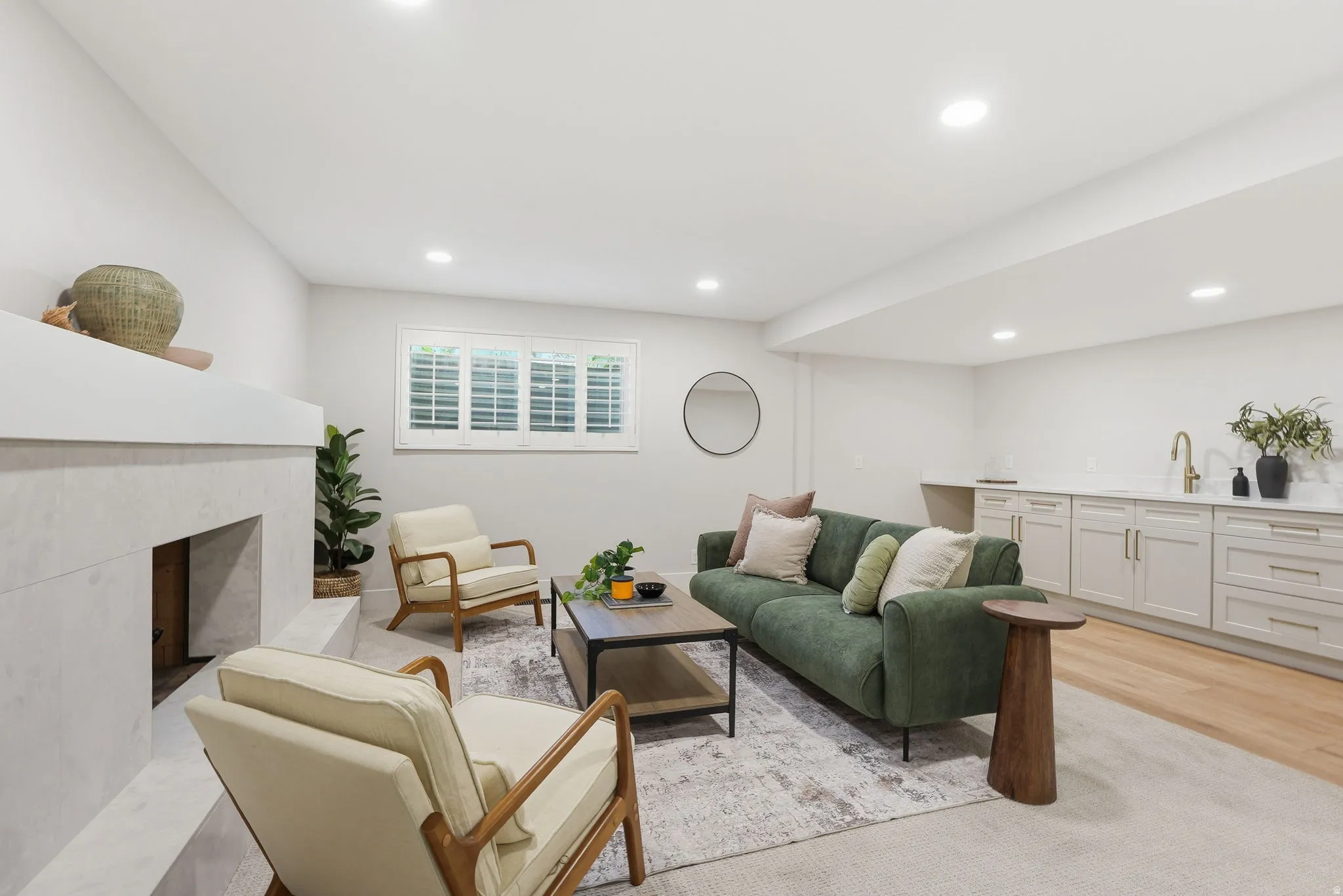 Living area featuring a modern fireplace with a light-colored surround, recessed lighting, and a built-in wet bar with a countertop and cabinetry