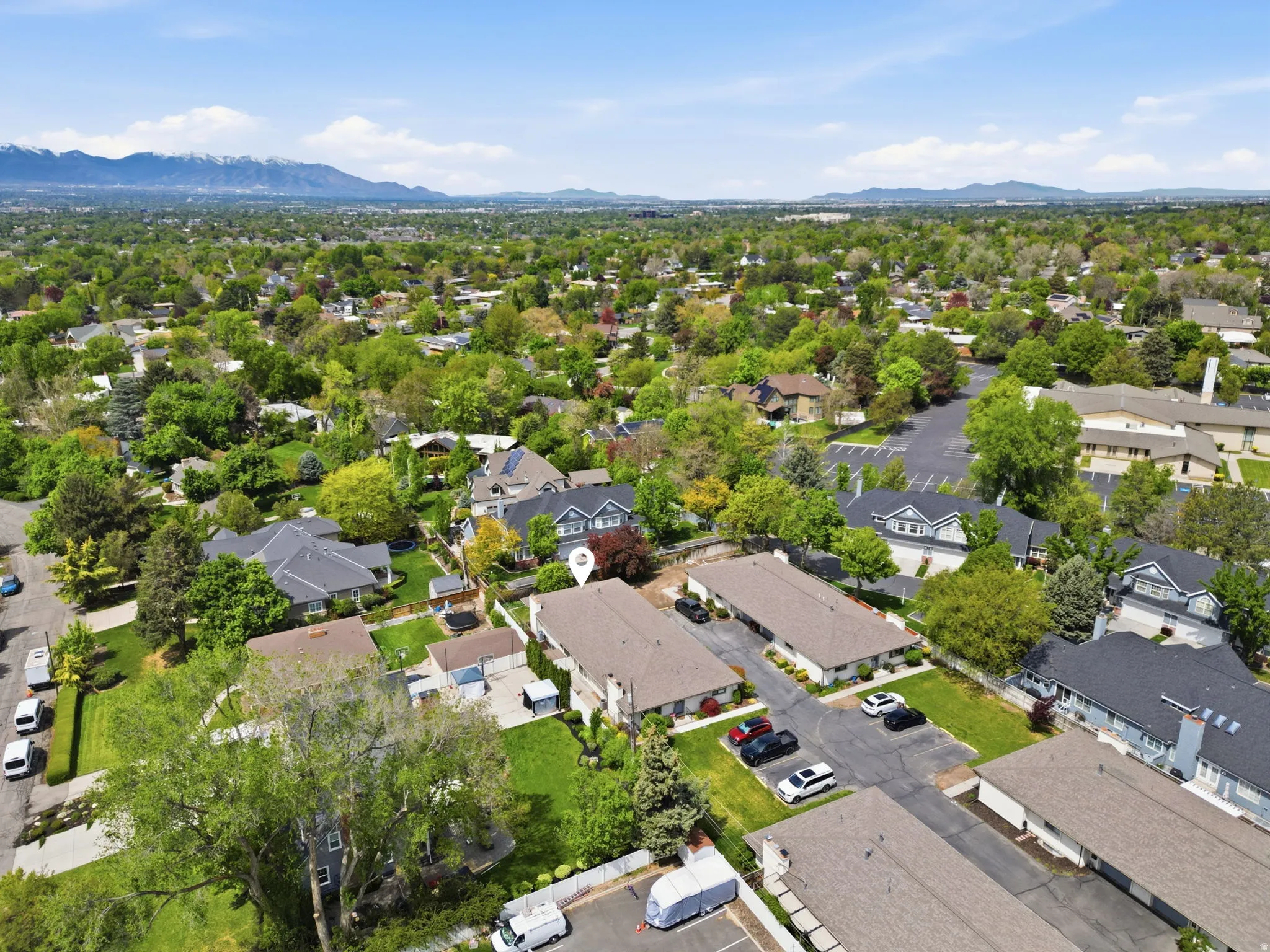 Aerial perspective showcasing a residential area with mature trees and mountain scenery