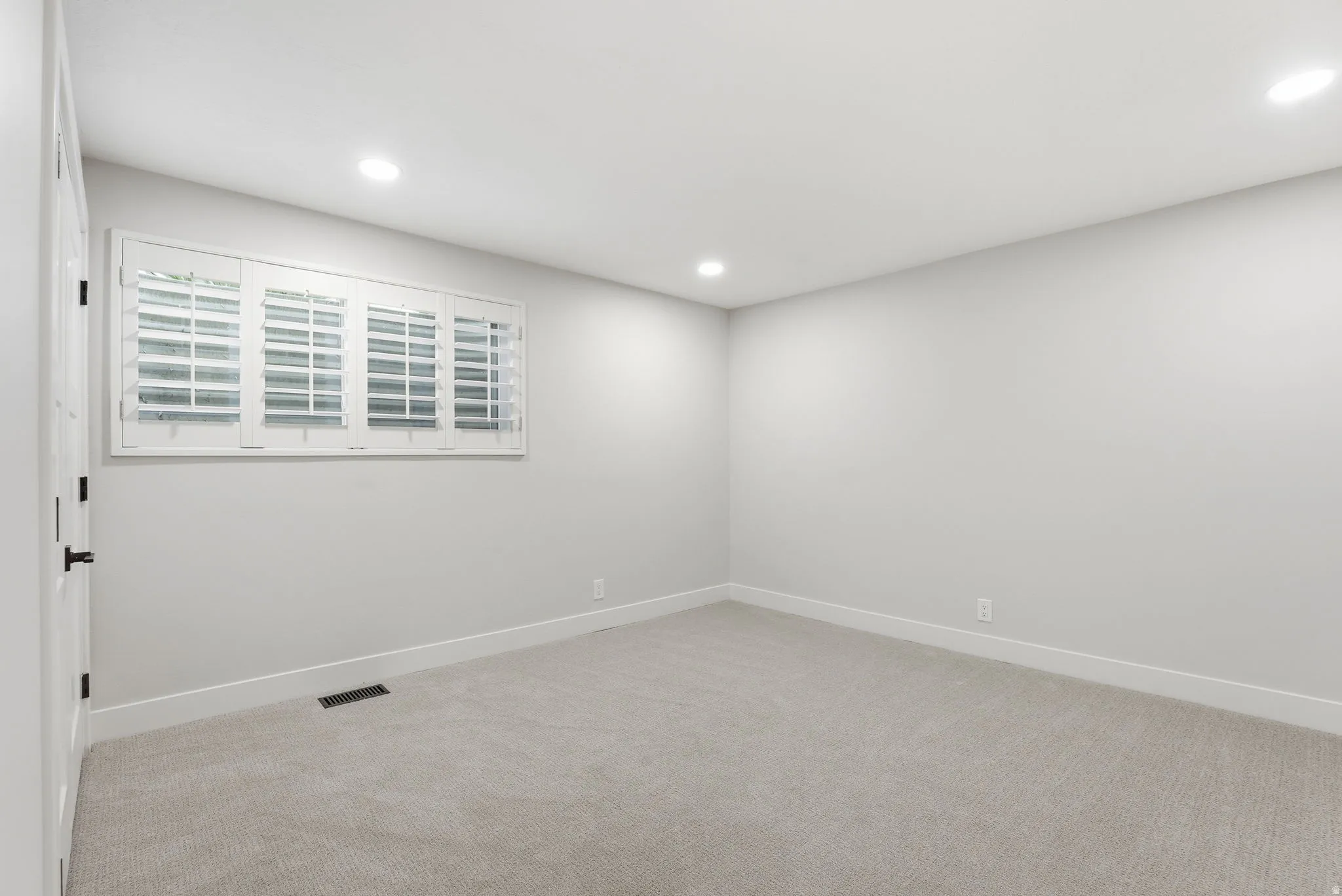 Neutral tone walls featuring a window with white plantation shutters