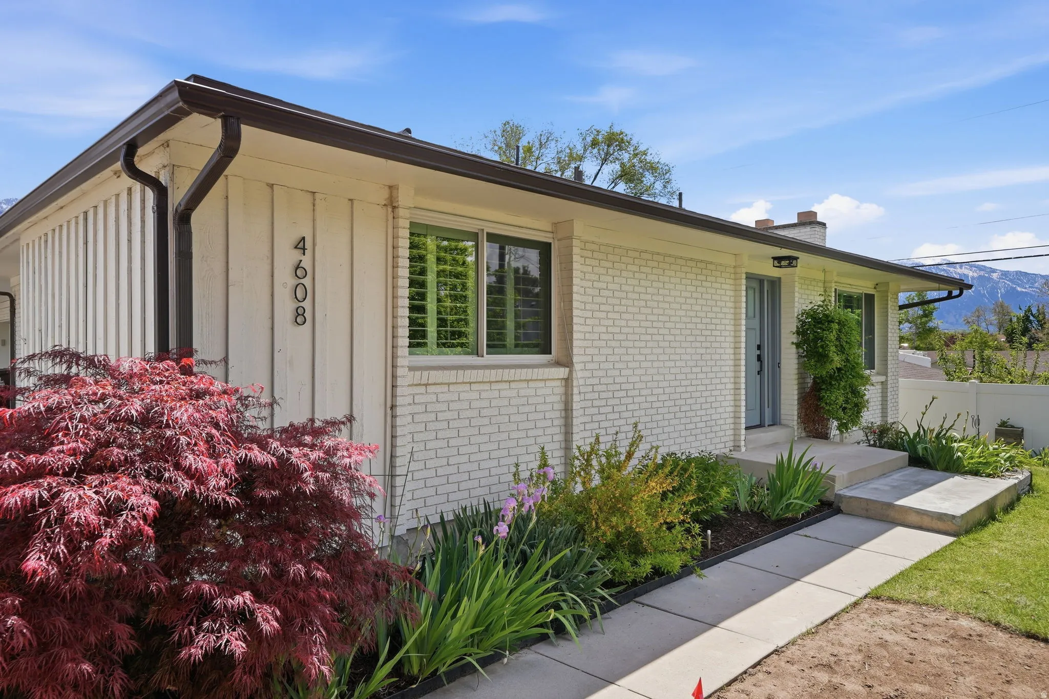 Exterior featuring white painted brick and vertical siding with dark gutters and trim
