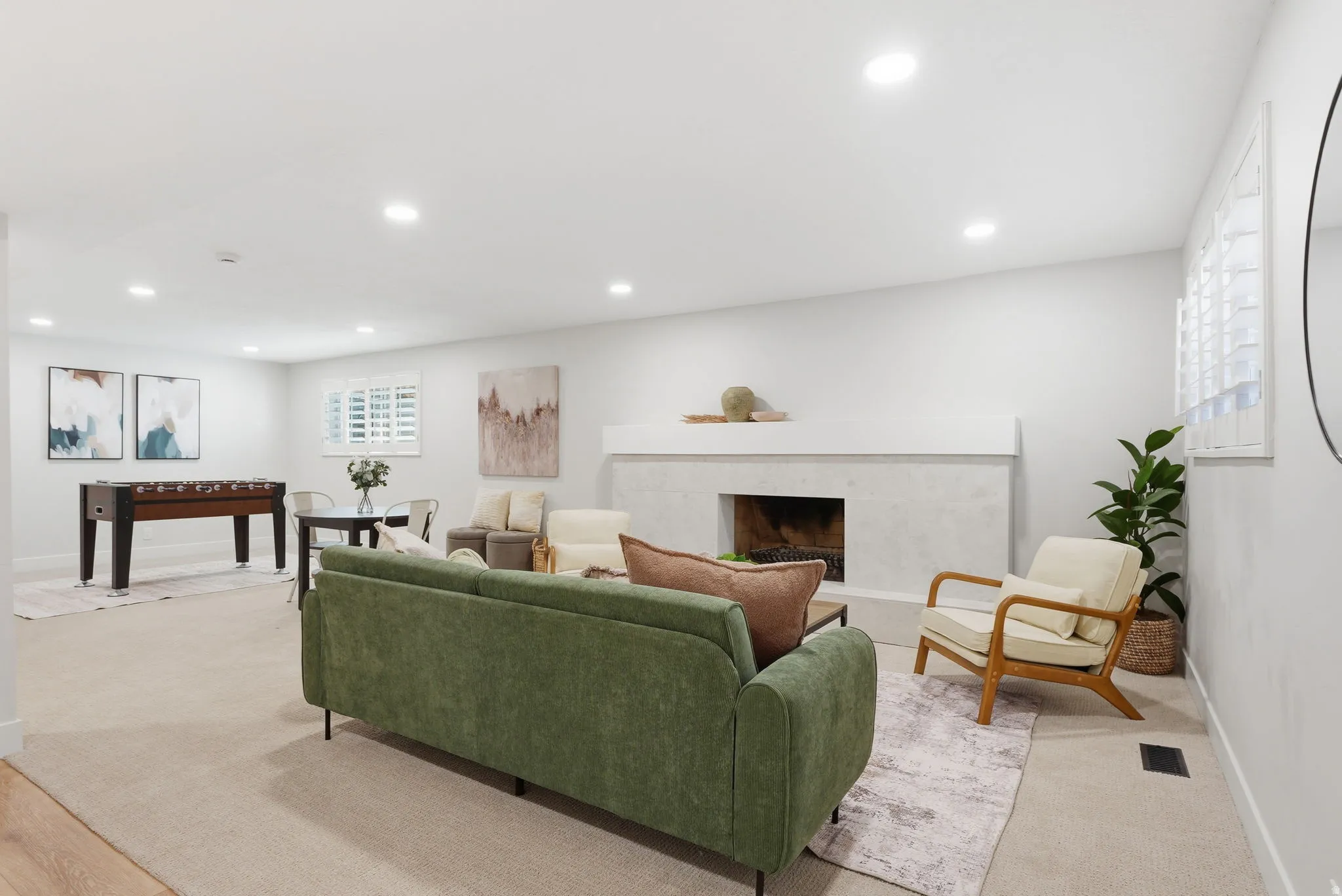 Spacious room featuring a fireplace with a light-colored mantel, recessed lighting, and light-tone carpeting
