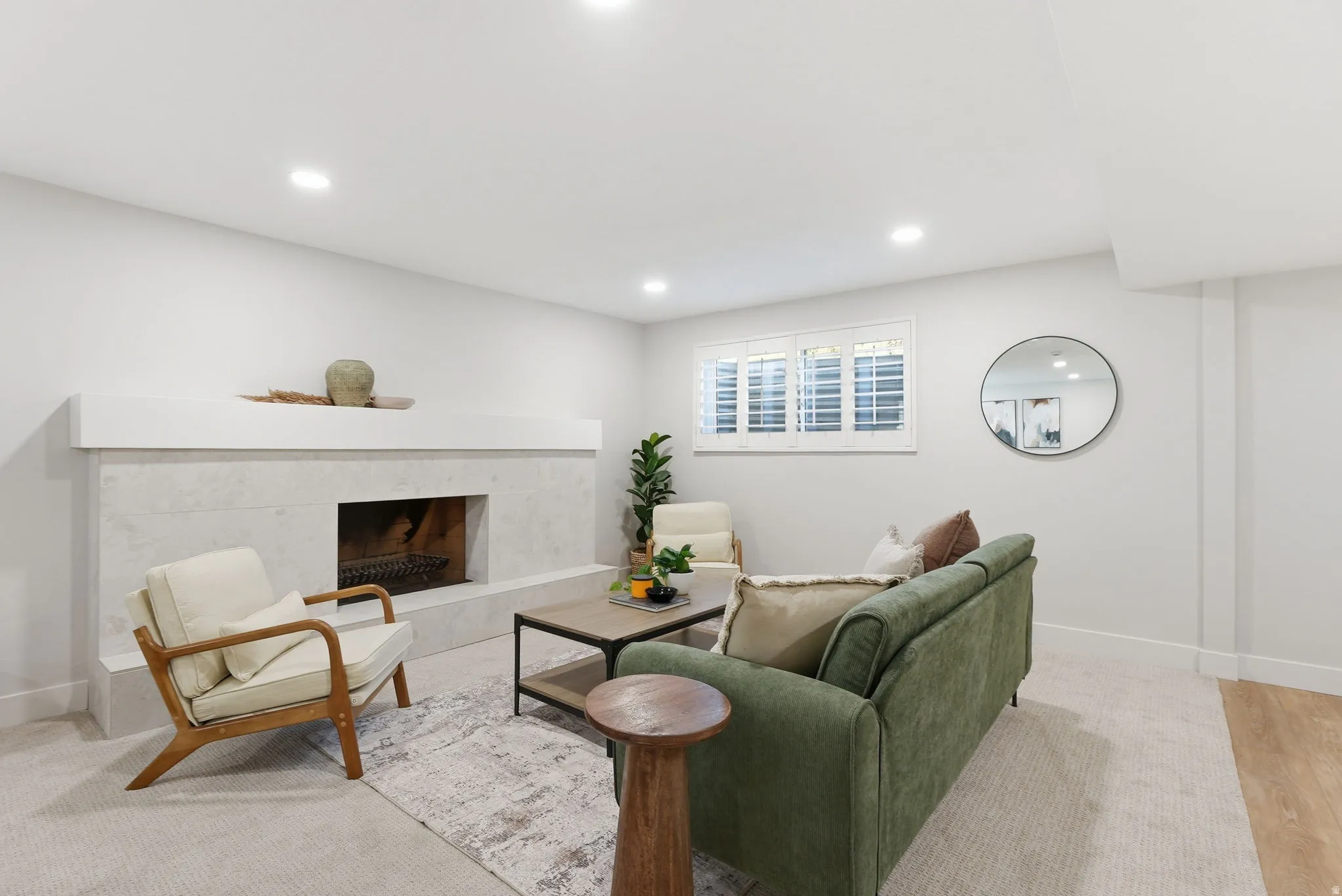 Living area featuring a textured fireplace with a mantel, recessed lighting, and a window with white louvered shutters