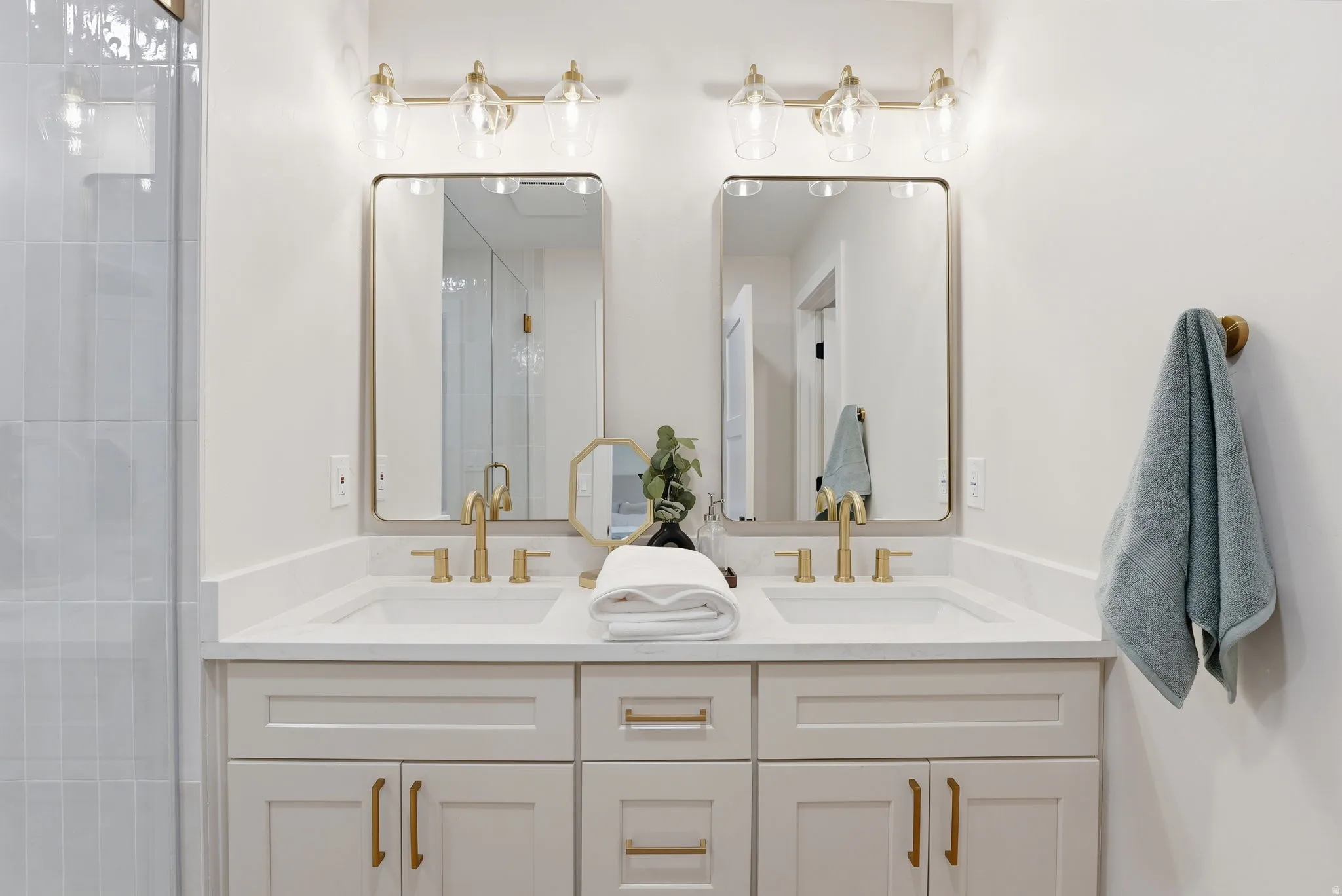 Dual vanity featuring white shaker cabinetry, quartz countertops, individual rectangular undermount sinks, and gold-finish fixtures