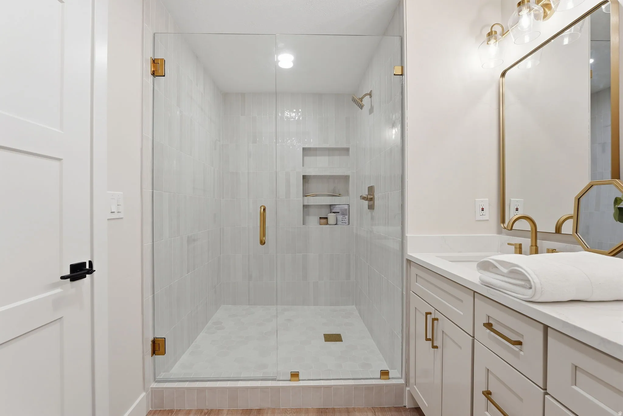 Walk-in shower with clear glass enclosure and gold-toned hardware