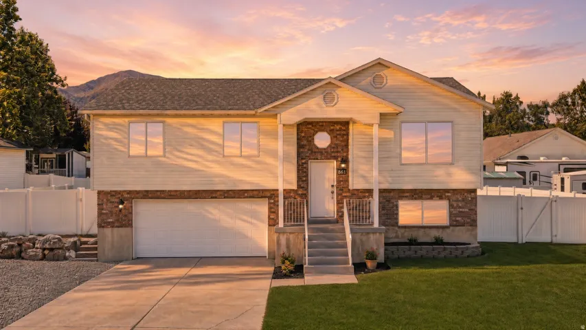 Two-story residence featuring a brick and siding exterior, front porch with columns, a two-car garage, and a concrete driveway