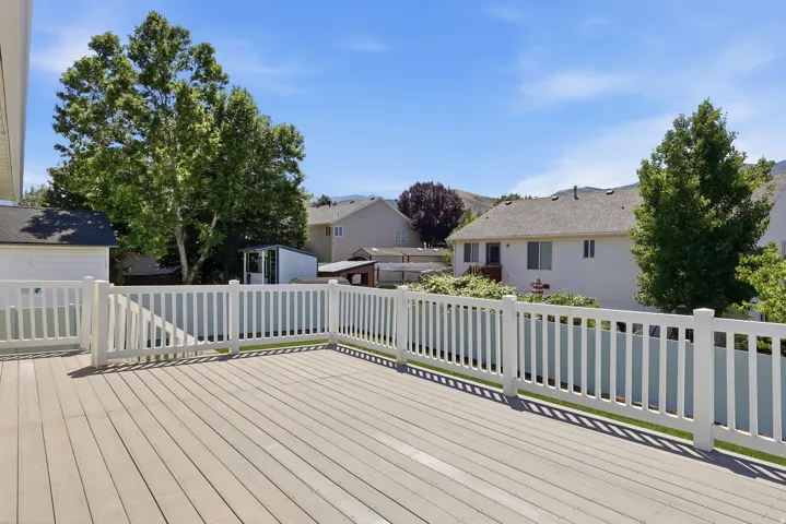 Spacious outdoor deck featuring composite decking and white vinyl railings, offering an elevated perspective of the surrounding area