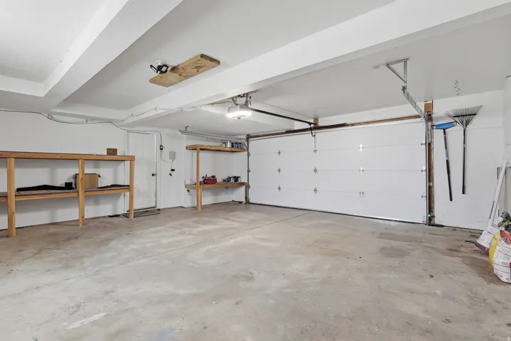 Spacious garage featuring a concrete floor, overhead lighting, an overhead garage door, and built-in shelving