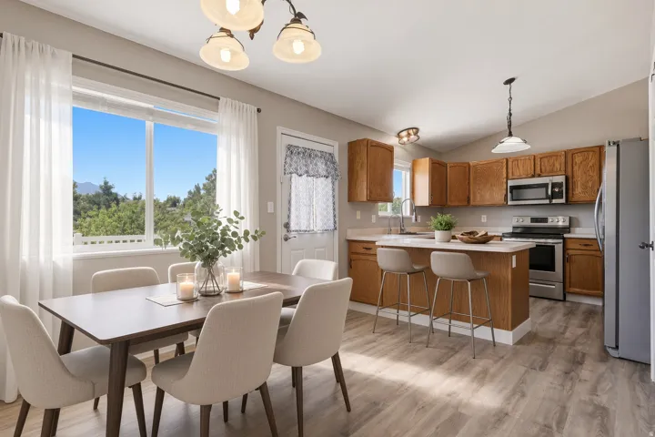 Kitchen and dining area featuring wood-finish flooring, a kitchen island with seating, stainless steel appliances, and a large window
