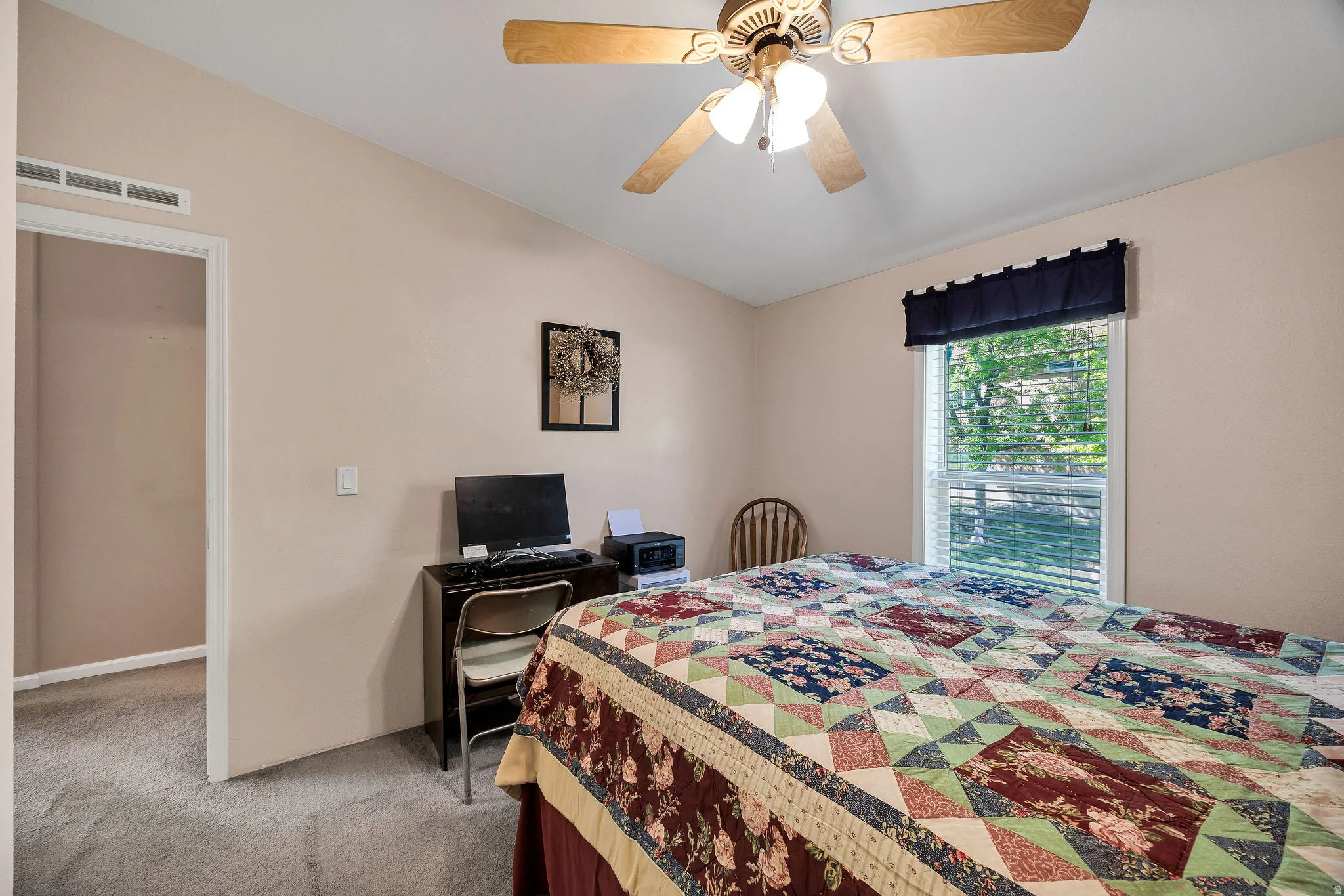 Carpeted room featuring an angled ceiling, a ceiling fan with light fixture, and a window with blinds