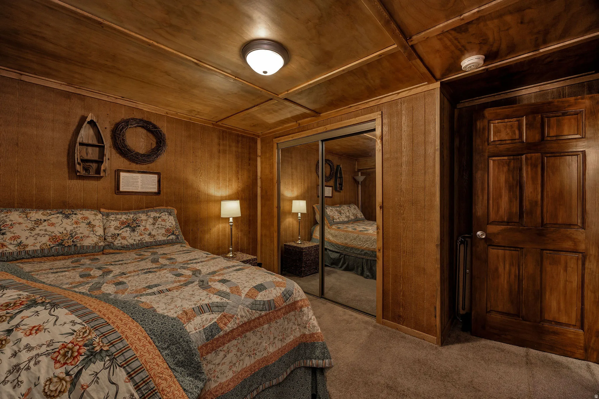 Wood-paneled room featuring a flush-mount ceiling light, wall paneling, and a mirrored closet door