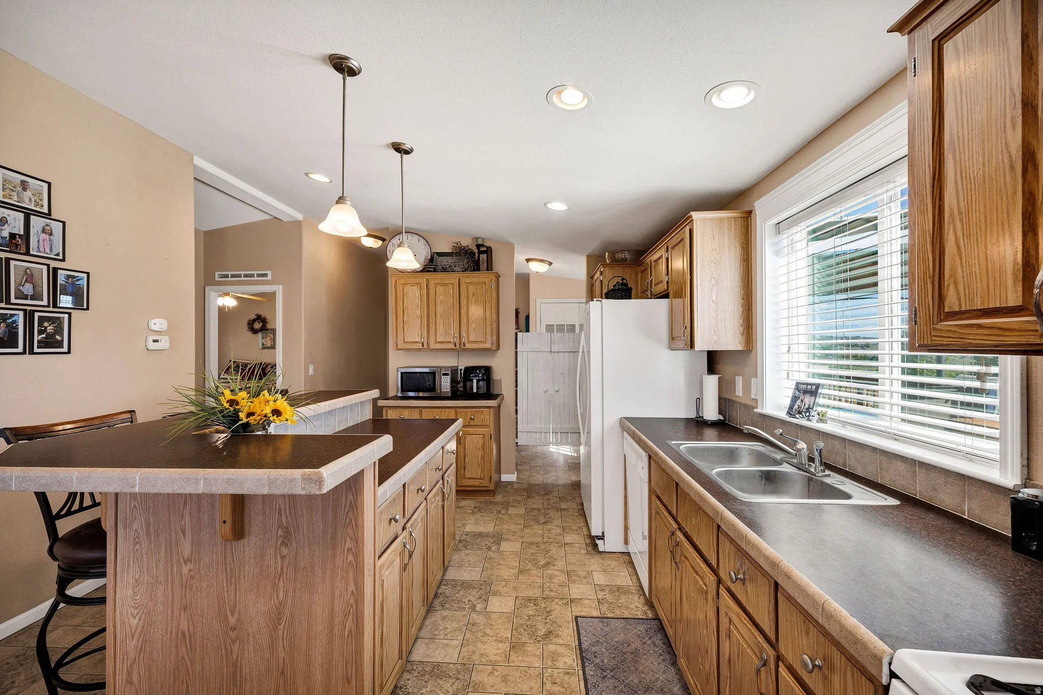 Spacious kitchen featuring wood-finish cabinetry, a large kitchen island with counter seating, and recessed lighting
