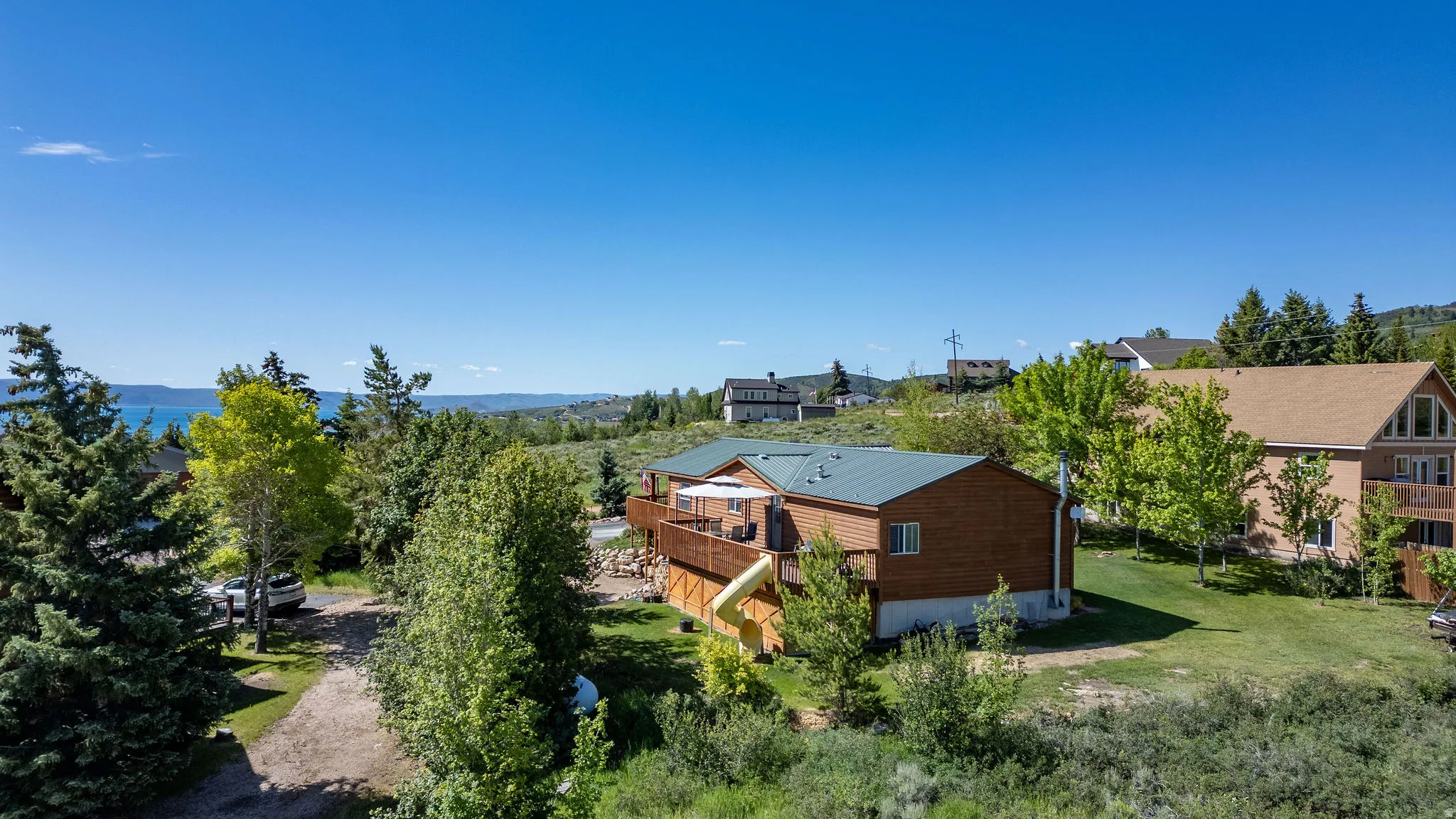 Wood-sided residence featuring a dark green metal roof, a spacious wooden deck, and a lower-level walkout
