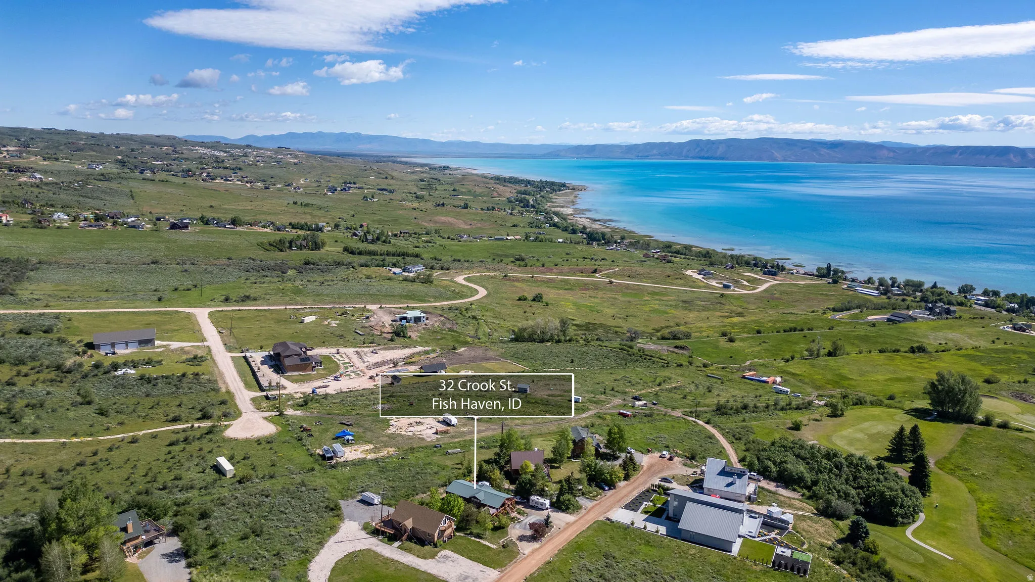 Expansive aerial overview showcasing a residential area with a prominent body of water, distant mountains, and varied terrain