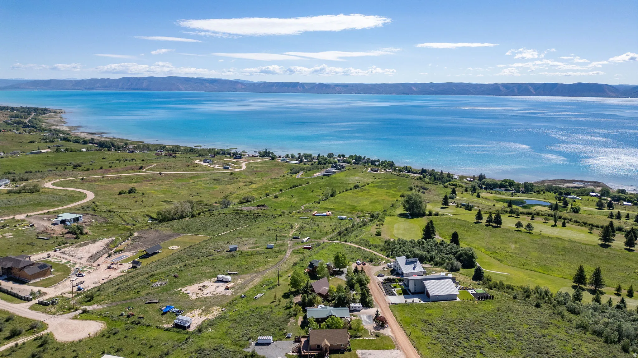 Expansive land parcel featuring distant mountain ranges and a large body of water with a shoreline