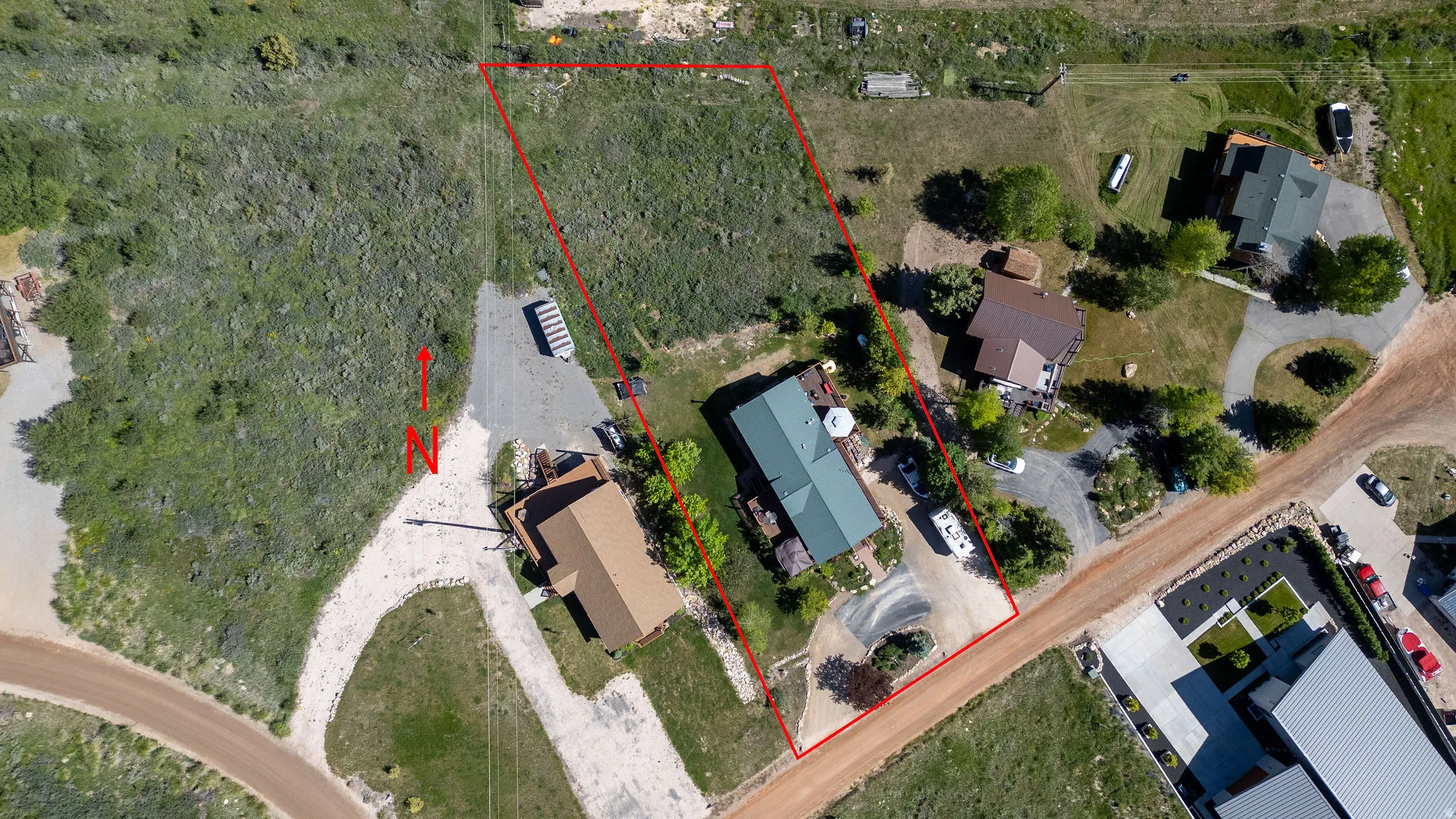 Expansive lot outlined in red, featuring natural vegetation and a gravel driveway