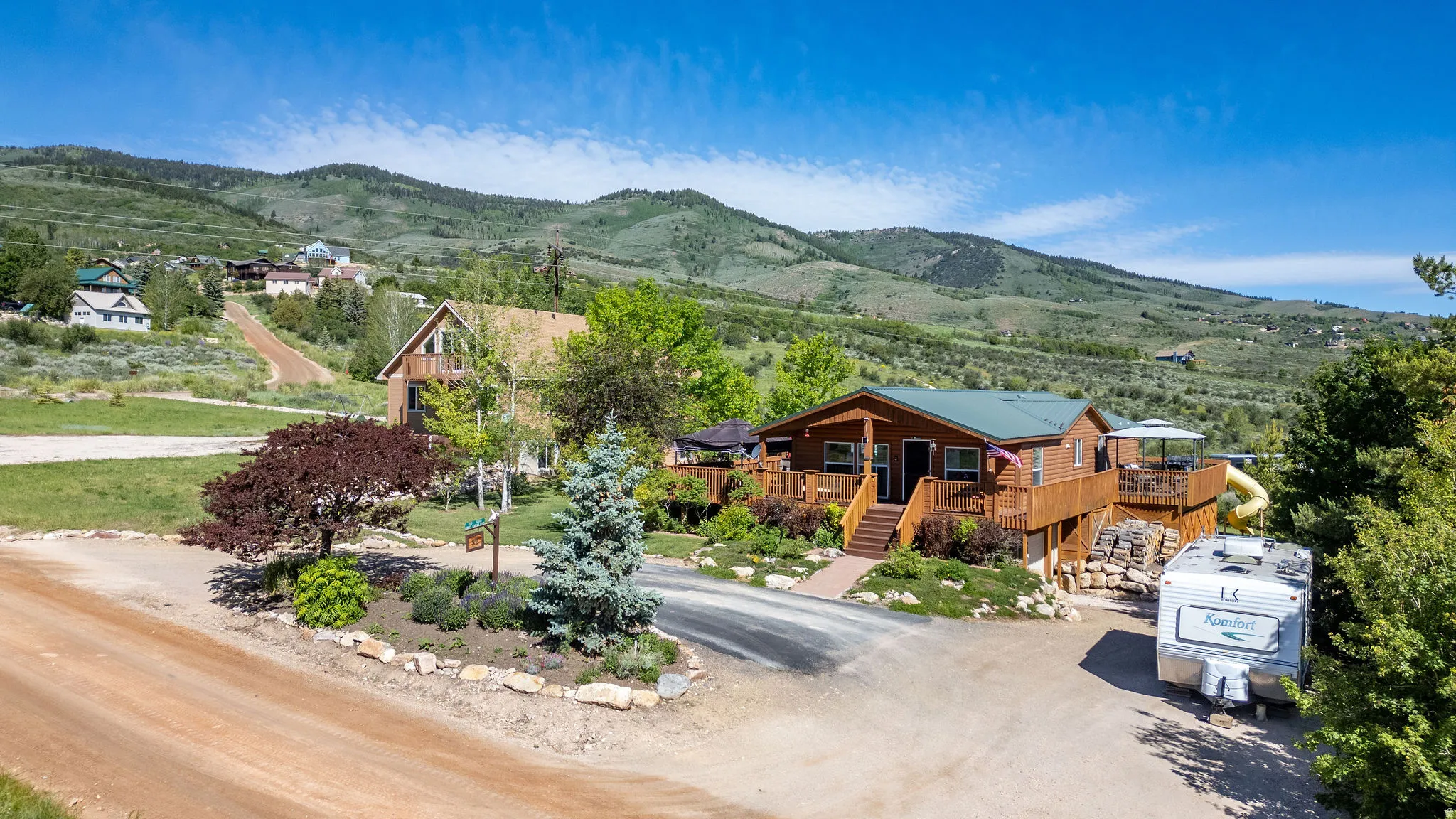 Wood-sided ranch-style residence featuring an elevated deck, multiple entryways, and a gravel driveway
