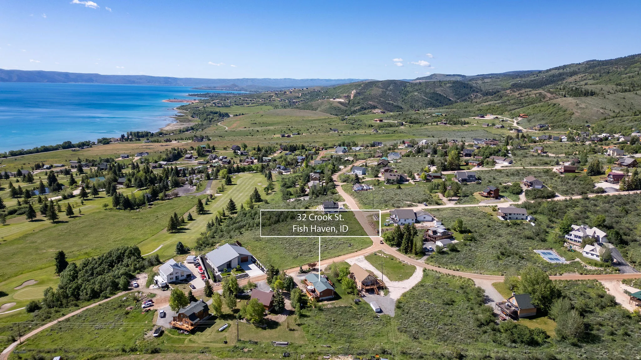 Aerial landscape featuring a vibrant lake, rolling hills, and a golf course