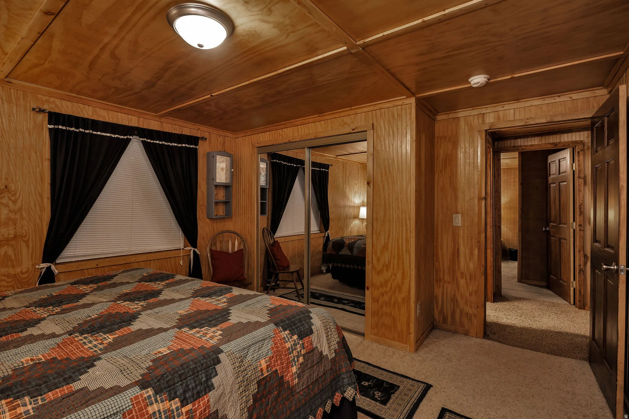 Bedroom featuring wood-paneled walls and ceiling, wall-to-wall carpeting, and a ceiling-mounted light fixture