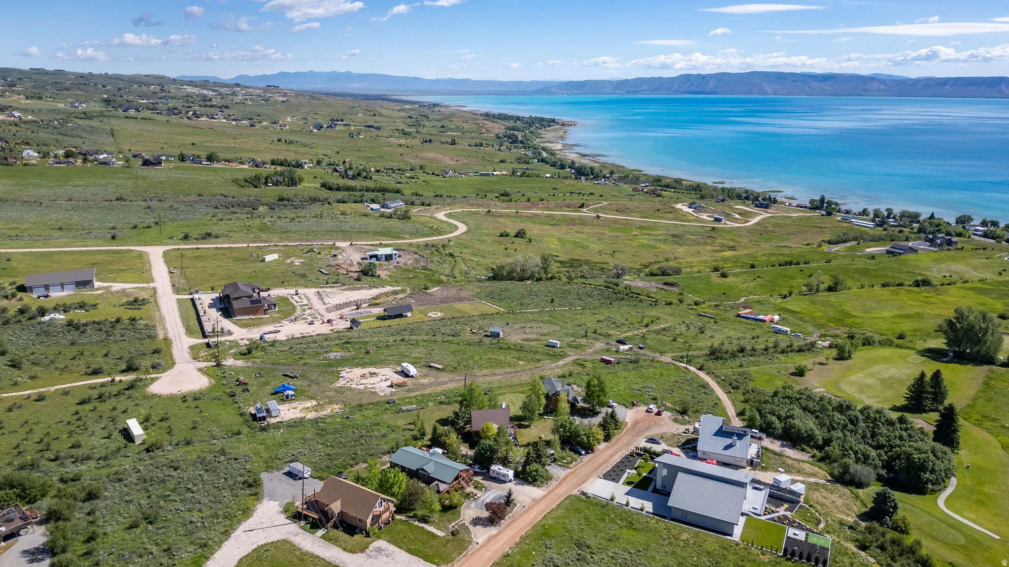Expansive land plots featuring a winding dirt road and scattered residential structures