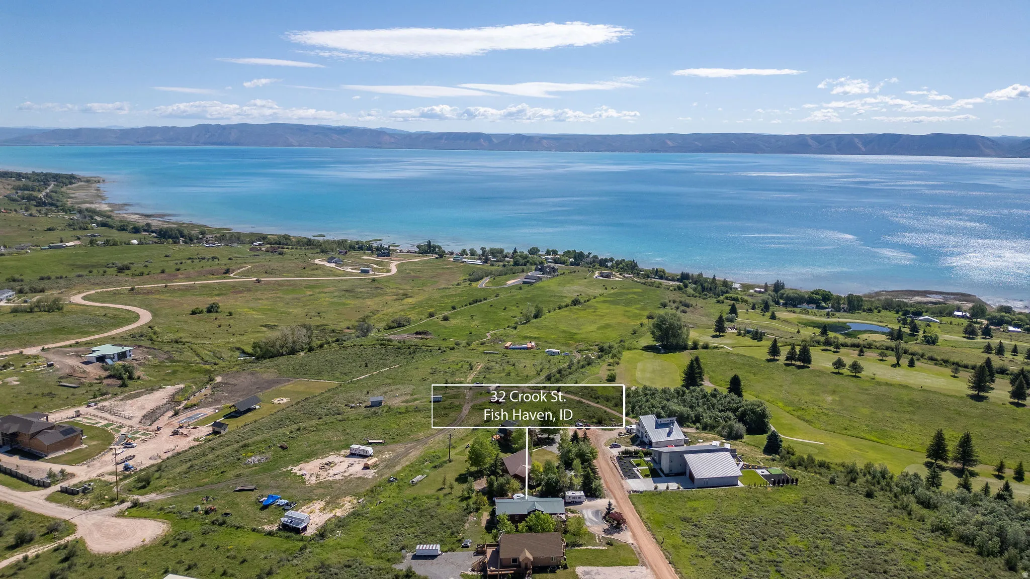Expansive waterfront property with a large body of water, rolling hills, and distant mountains