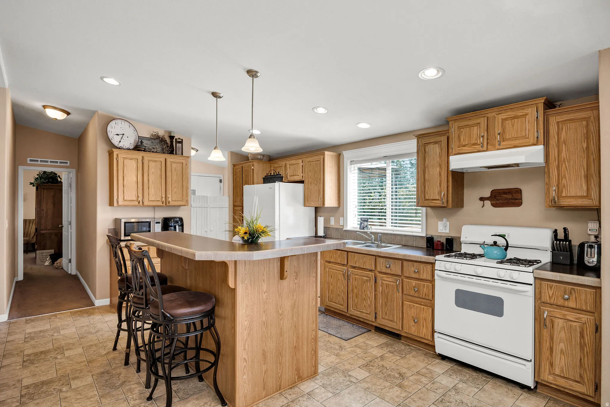 Kitchen featuring wood cabinetry, laminate countertops, and a built-in breakfast bar with pendant lighting