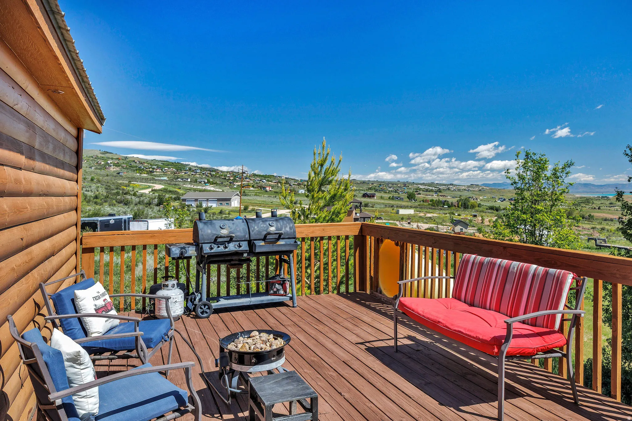 Expansive wood deck with a durable wood railing, featuring a log cabin style exterior wall