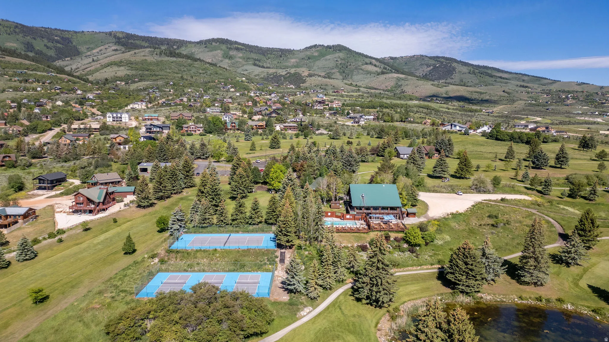 Expansive property featuring a multi-story structure with a green roof, multiple tennis courts, and a swimming pool with an accompanying deck