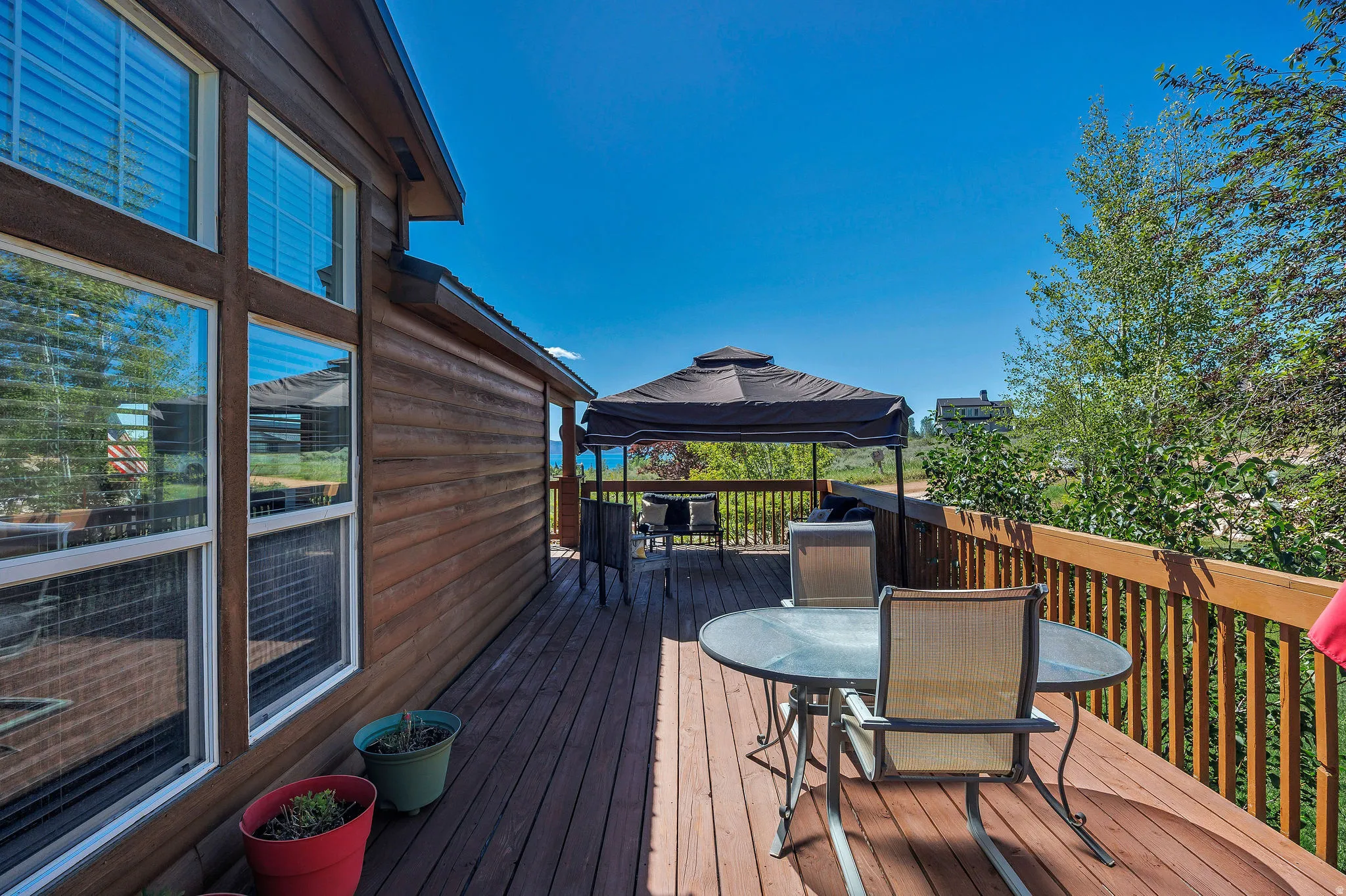 Spacious wooden deck featuring a gazebo, wood siding, and large windows