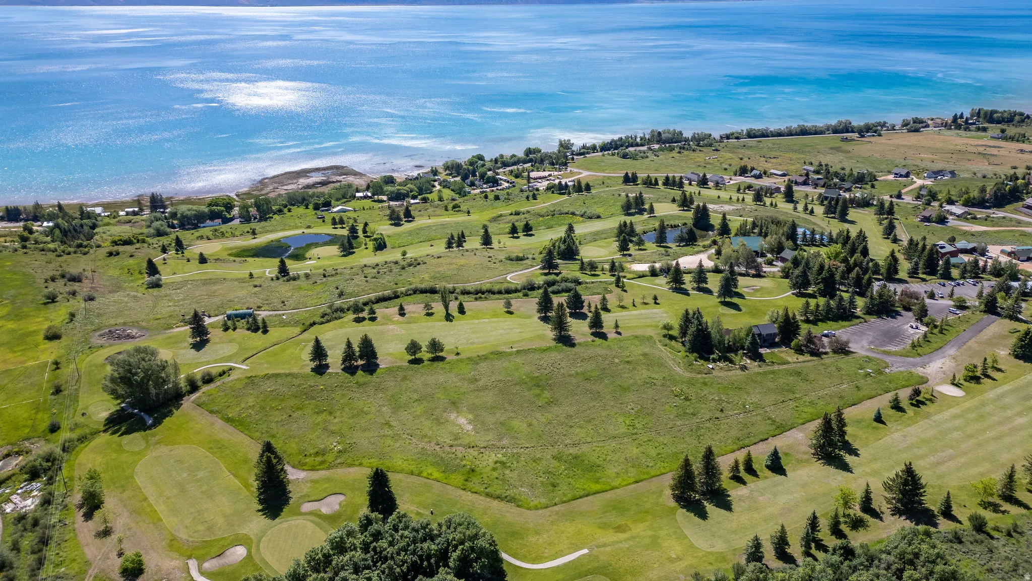 Expansive waterfront landscape featuring a golf course, multiple water features, and a variety of mature trees