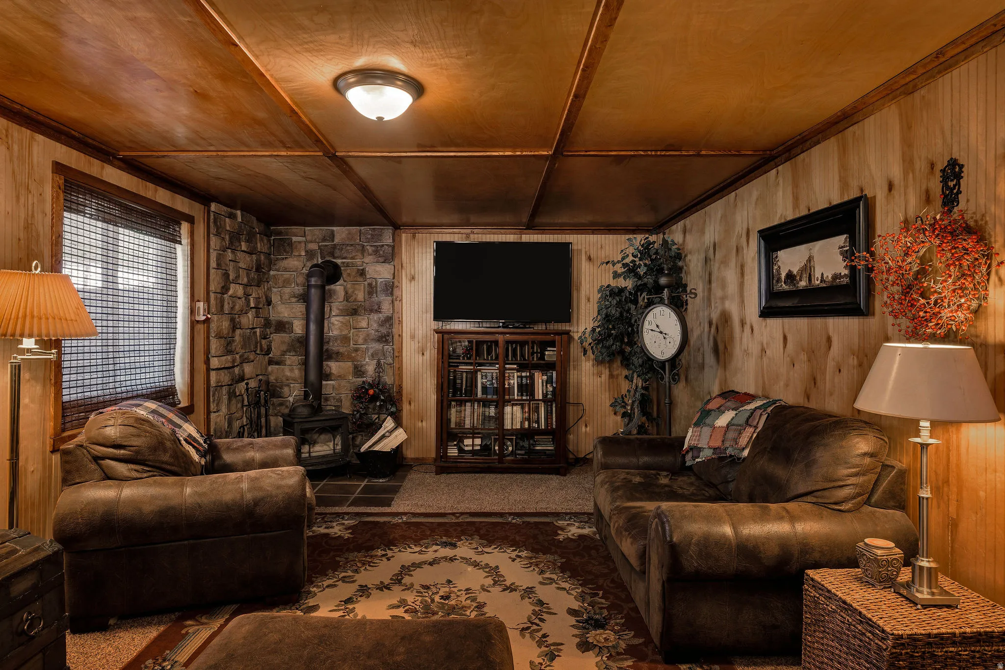 Living area with wood paneling, wood-finish ceiling, and a prominent stone accent wall