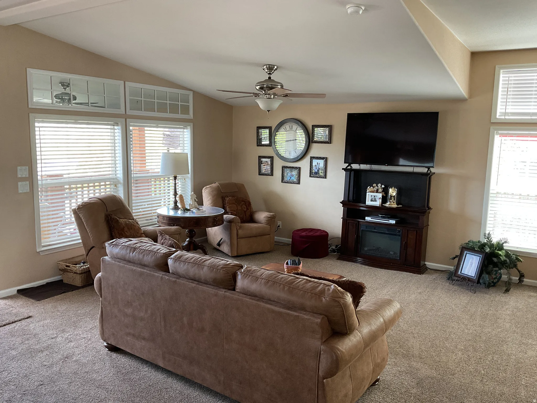 Spacious living area featuring a vaulted ceiling and neutral-toned carpeting
