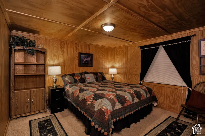 Bedroom featuring wood-finish wall paneling, a wood-finish slatted ceiling, and neutral carpeting