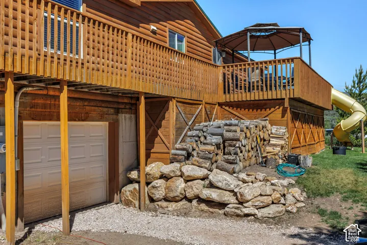 Wood-sided exterior featuring a two-story wood deck with railings, an attached gazebo, and a yellow tube slide