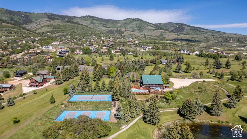 Expansive property featuring a multi-story structure with a green roof, multiple tennis courts, and a swimming pool with an accompanying deck