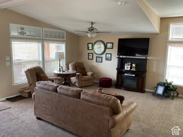 Spacious living area featuring a vaulted ceiling and neutral-toned carpeting