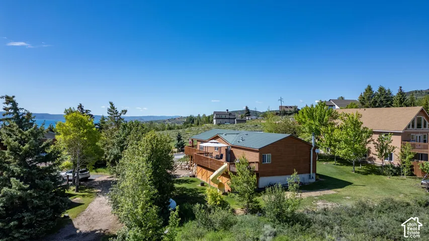Wood-sided residence featuring a dark green metal roof, a spacious wooden deck, and a lower-level walkout