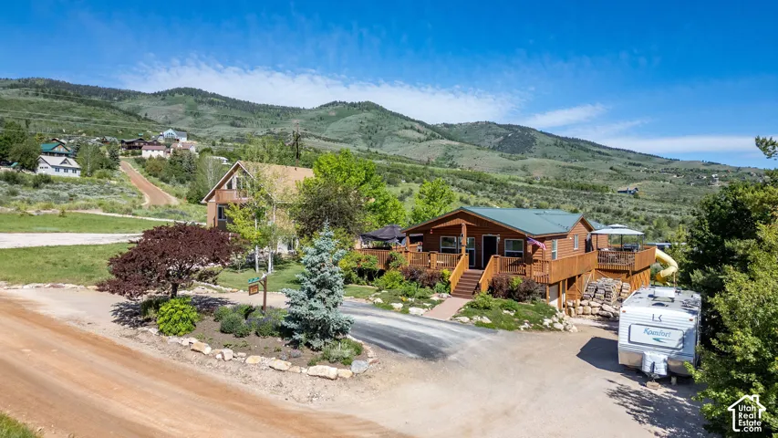 Wood-sided ranch-style residence featuring an elevated deck, multiple entryways, and a gravel driveway