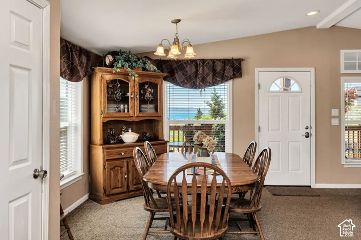 Spacious interior featuring high ceilings, light brown carpeting, multiple windows with horizontal blinds, and a white paneled exterior door with an arched glass insert