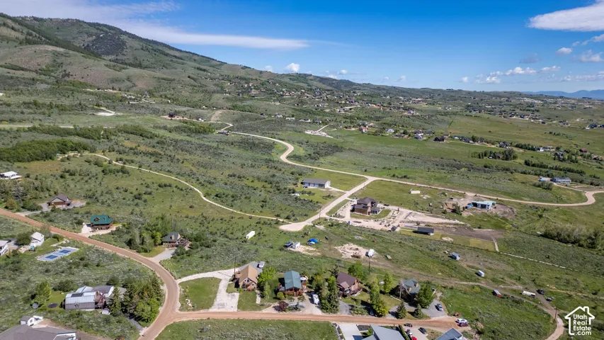 Expansive rural landscape featuring rolling hills and scattered residences under a clear blue sky