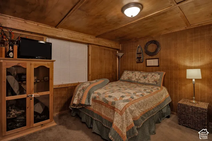 Wood-paneled room featuring a window with horizontal blinds, overhead flush mount lighting, and wood-finish flooring
