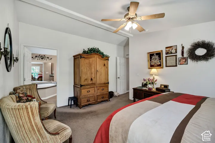 Carpeted bedroom with a vaulted ceiling and a ceiling fan with integrated lighting