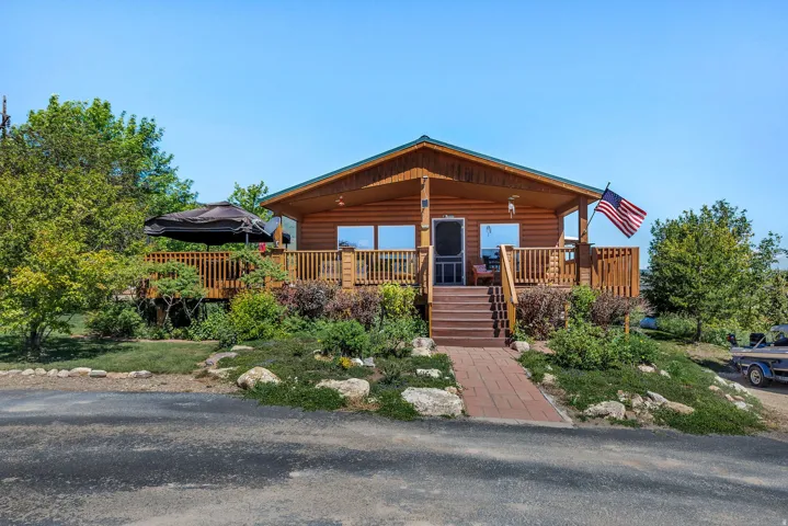 Wood-sided home with a covered front porch, an expansive wooden deck, and a red brick pathway