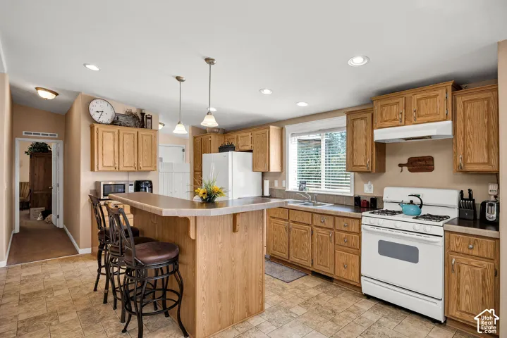 Kitchen featuring wood cabinetry, laminate countertops, and a built-in breakfast bar with pendant lighting