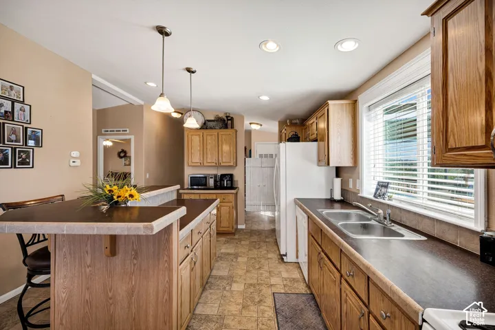 Spacious kitchen featuring wood-finish cabinetry, a large kitchen island with counter seating, and recessed lighting