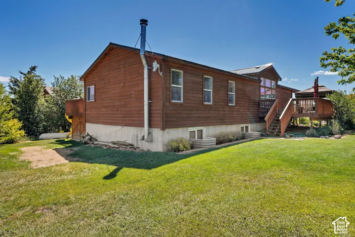 Wood-sided property with a visible foundation, featuring a large exterior deck with wooden stairs